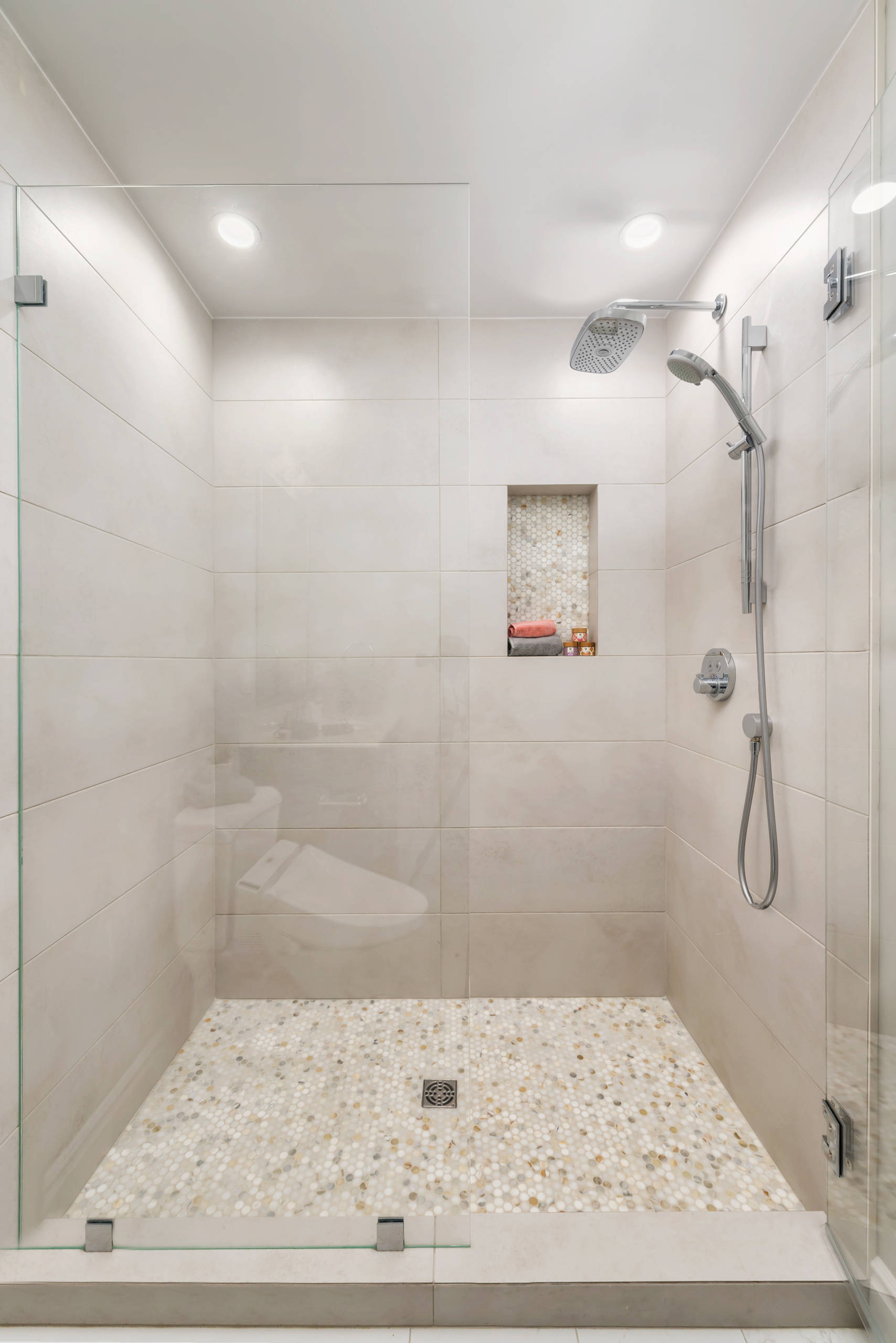 Large format white tile shower with penny mosaic floor